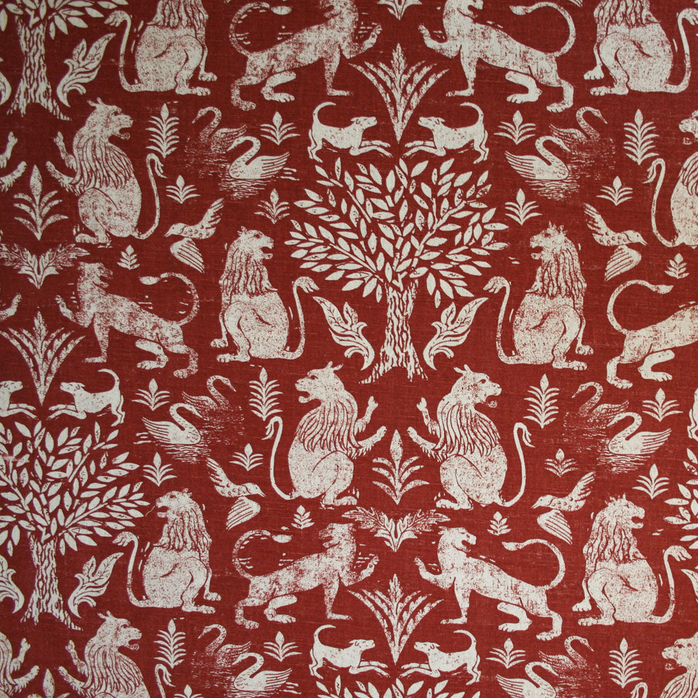 Detail of fabric in a lion and plant print in white on a mottled red field.