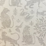 Close-up of fabric in a lion and plant print in gray on a mottled cream field.