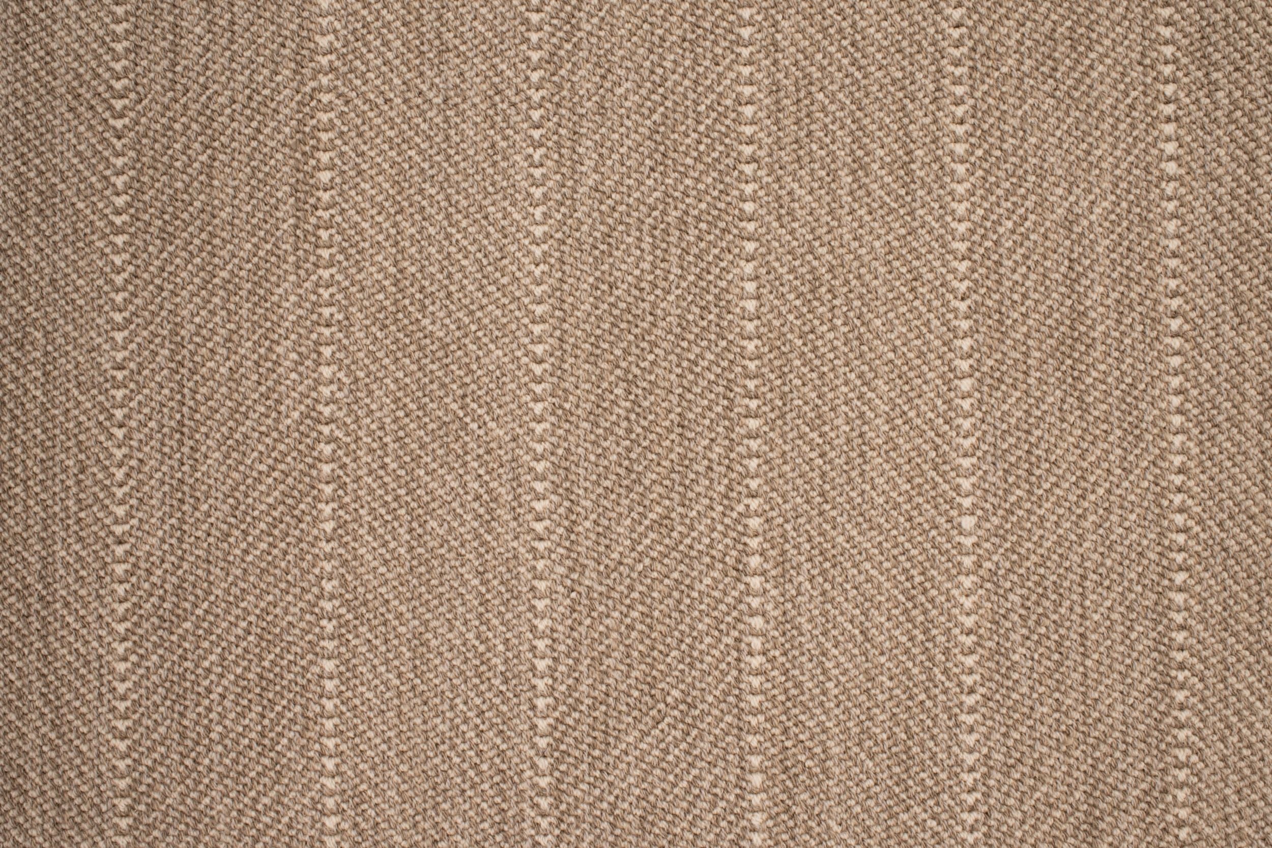 Close up of a broadloom carpet with a herringbone stripe in brown.