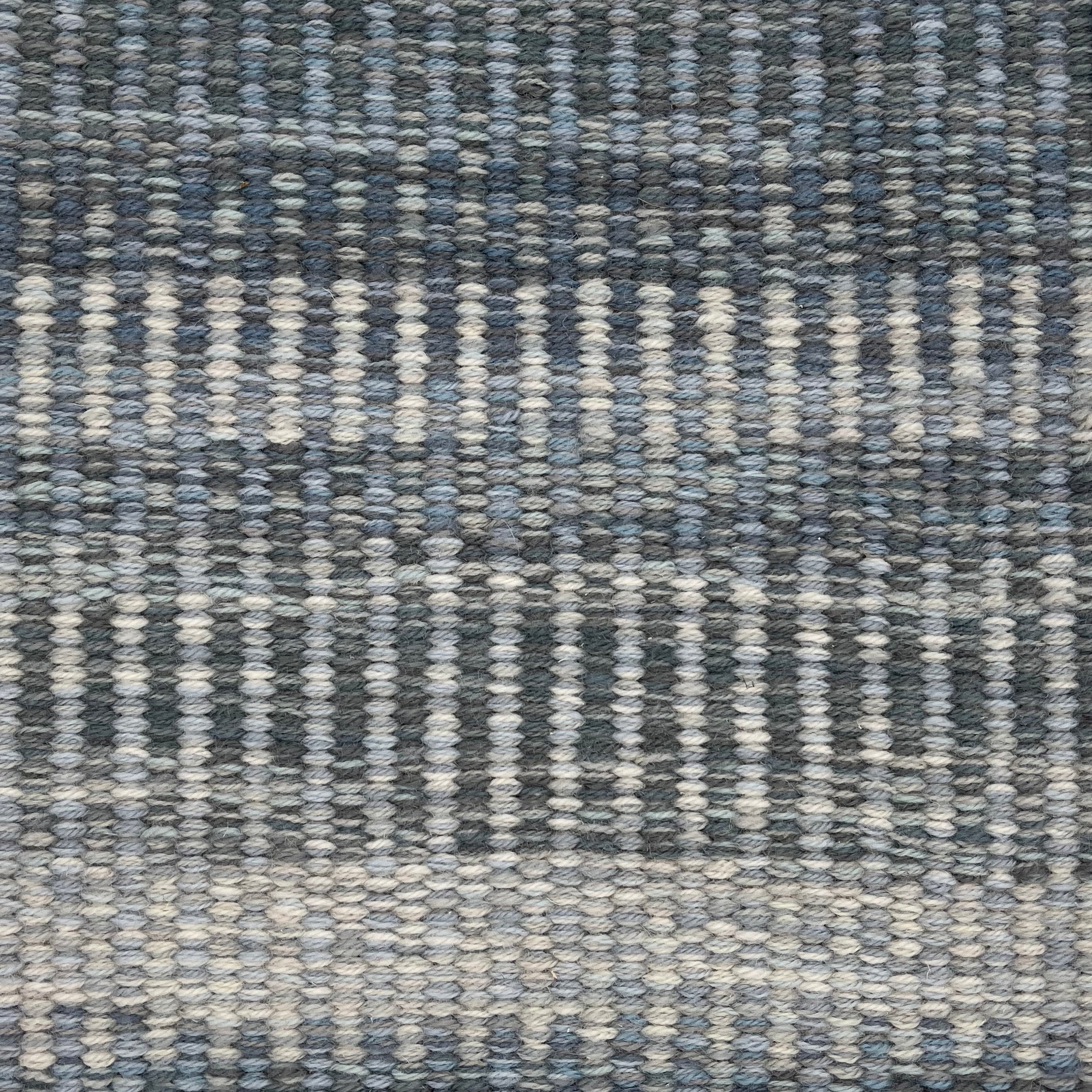 Handwoven rug detail in a textural stripe design in slate and grey