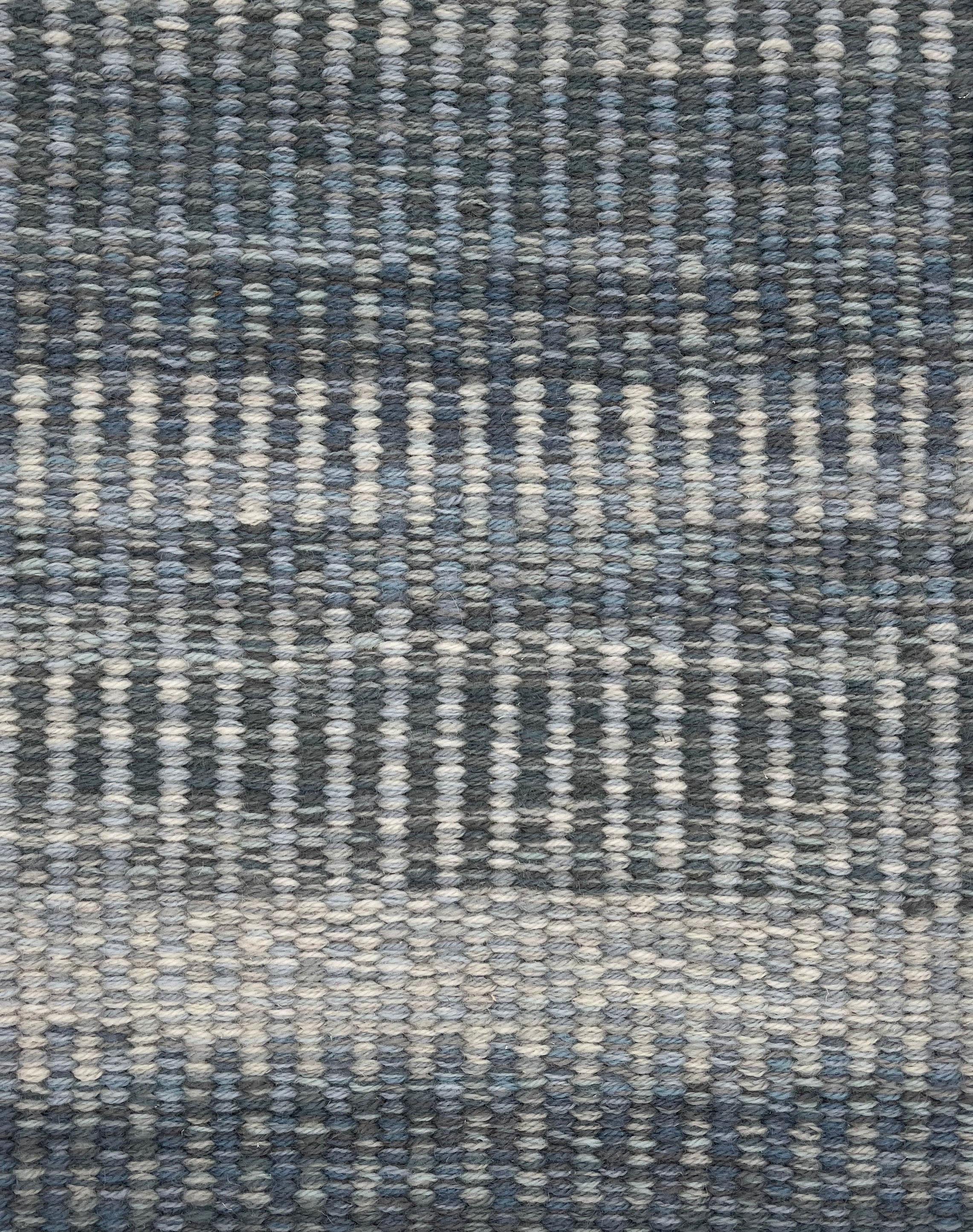 Handwoven rug detail in a textural stripe design in slate and grey