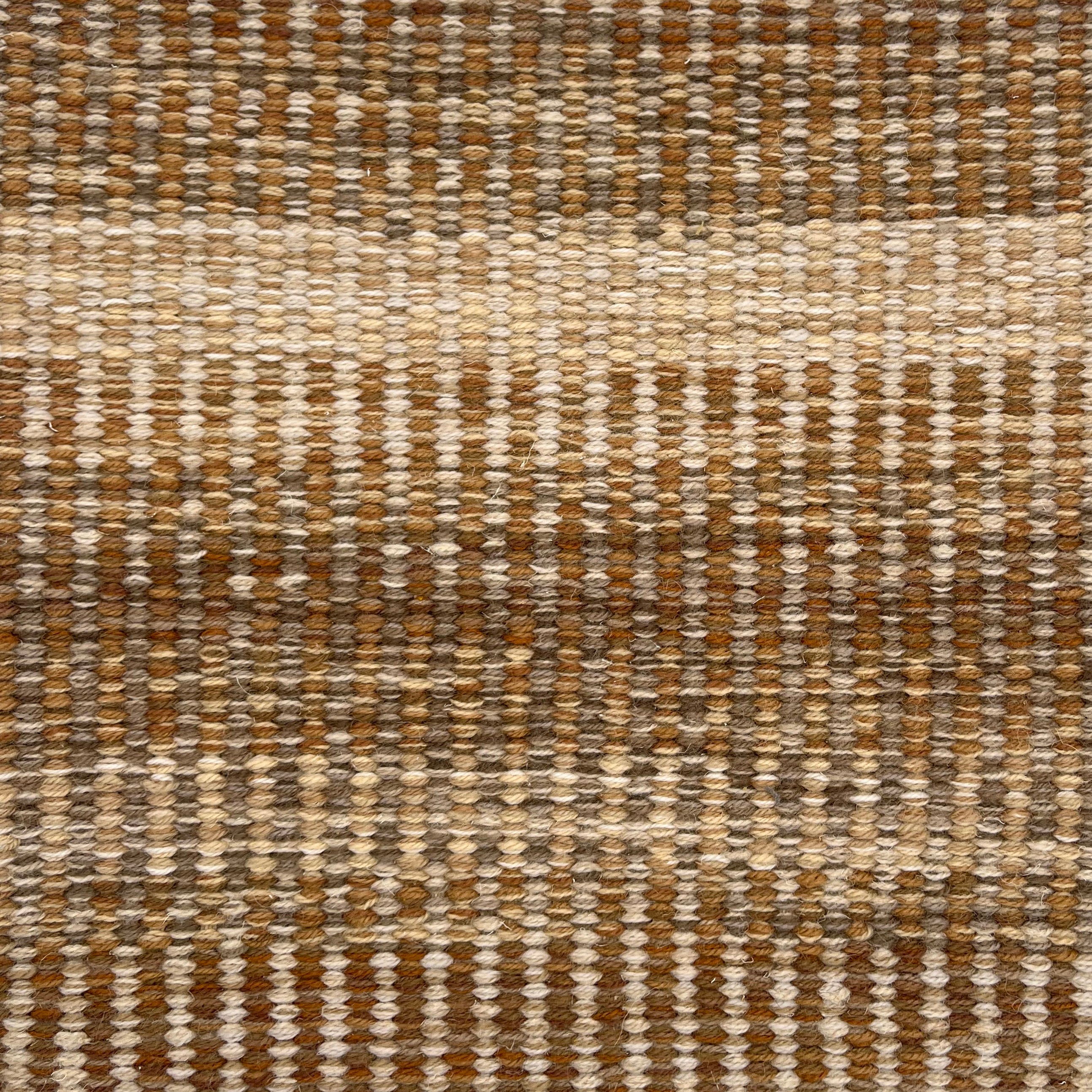 Handwoven rug detail in a textural stripe design in tan and beige