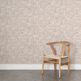 A wooden chair stands in front of a wall papered in a linear check pattern in shades of brown on a cream field.