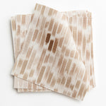 A stack of fabric swatches in a linear check pattern in shades of tan and brown on a white field.