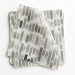 A stack of fabric swatches in a linear check pattern in shades of gray on a white field.