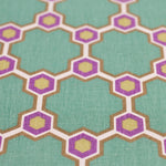Fabric yardage in a geometric honeycomb pattern in shades of green, purple, white and orange.