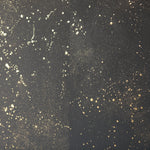 Detail of a wallpaper in a random splattered pattern in metallic gold on a black field.