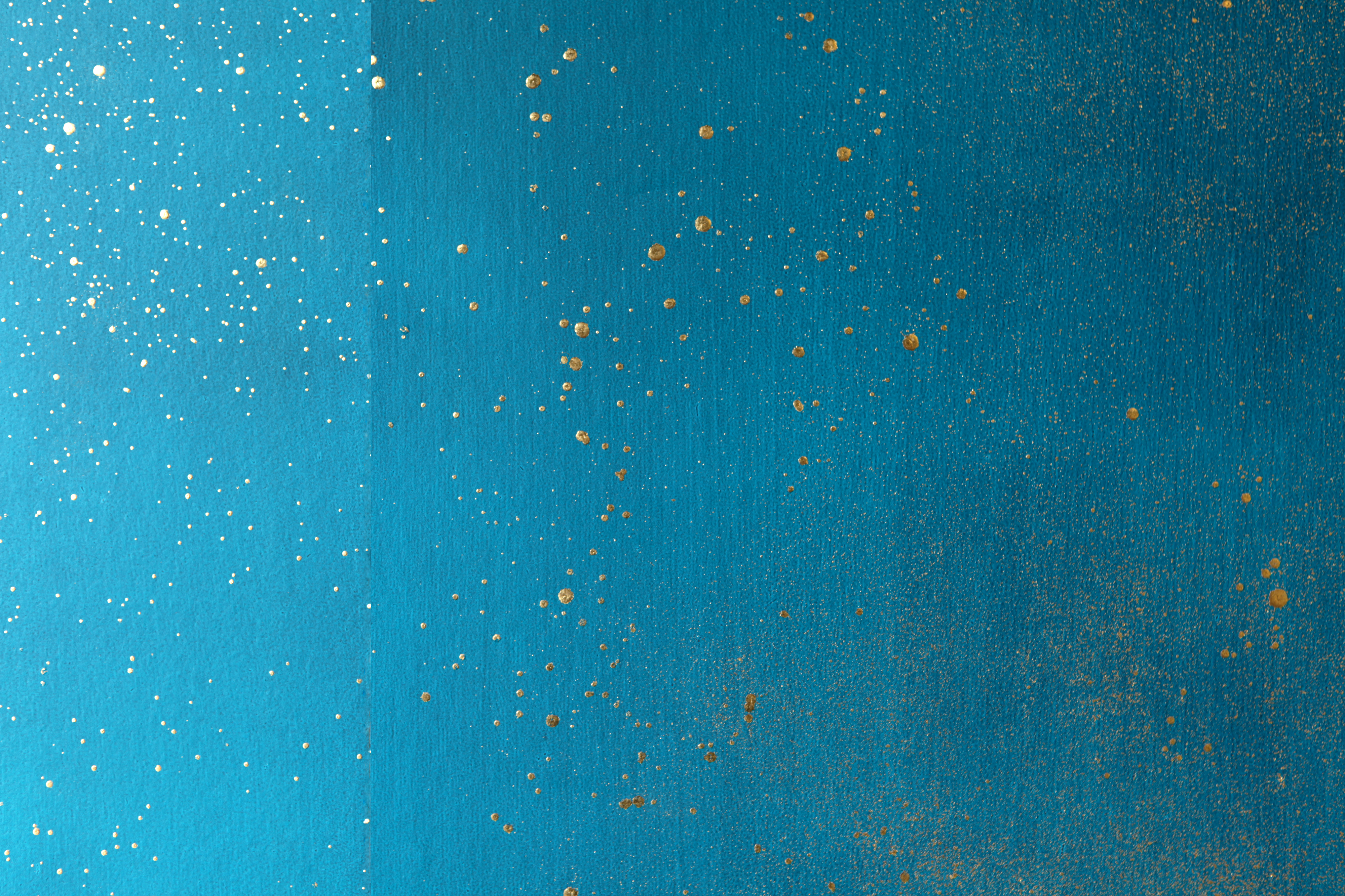 Detail of a wallpaper in a random splattered pattern in metallic gold on a blue field.