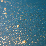 Wide-angle shot of wallpaper in a random splattered pattern in metallic gold on a blue field.