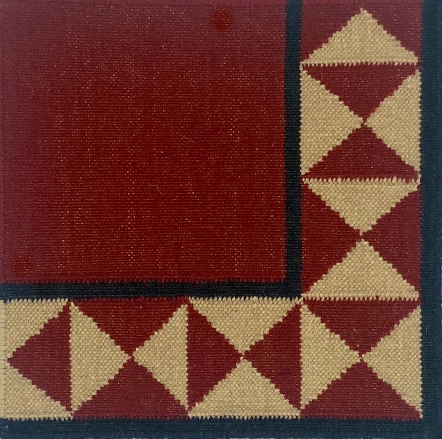 Close-up of a flatweave rug with a diamond border  pattern in red, ream and black