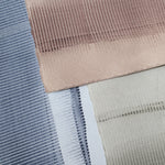 Pile of wallpaper swatches with dimensional combed patterns in navy, mauve and tan colorways.