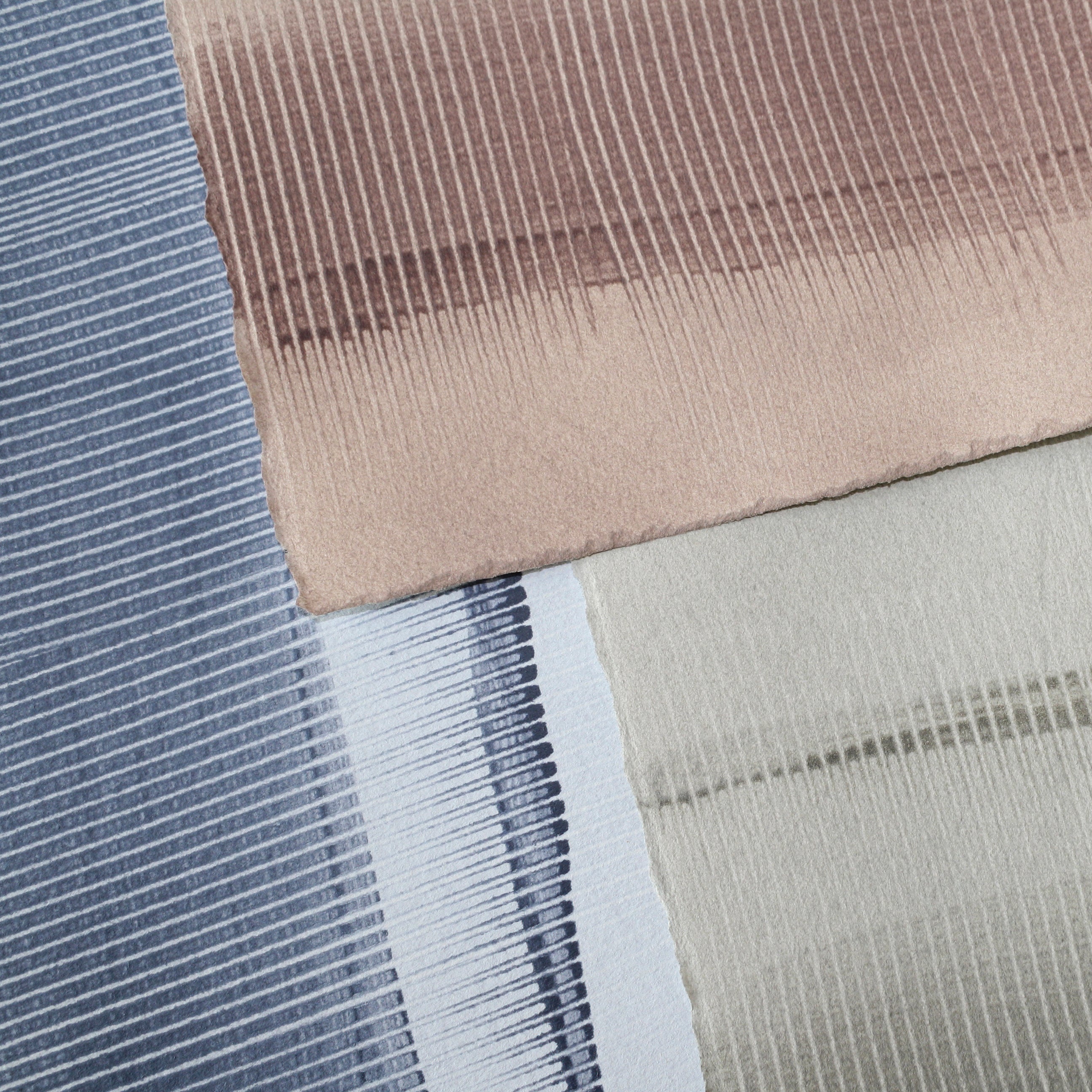 Pile of wallpaper swatches with dimensional combed patterns in navy, mauve and tan colorways.