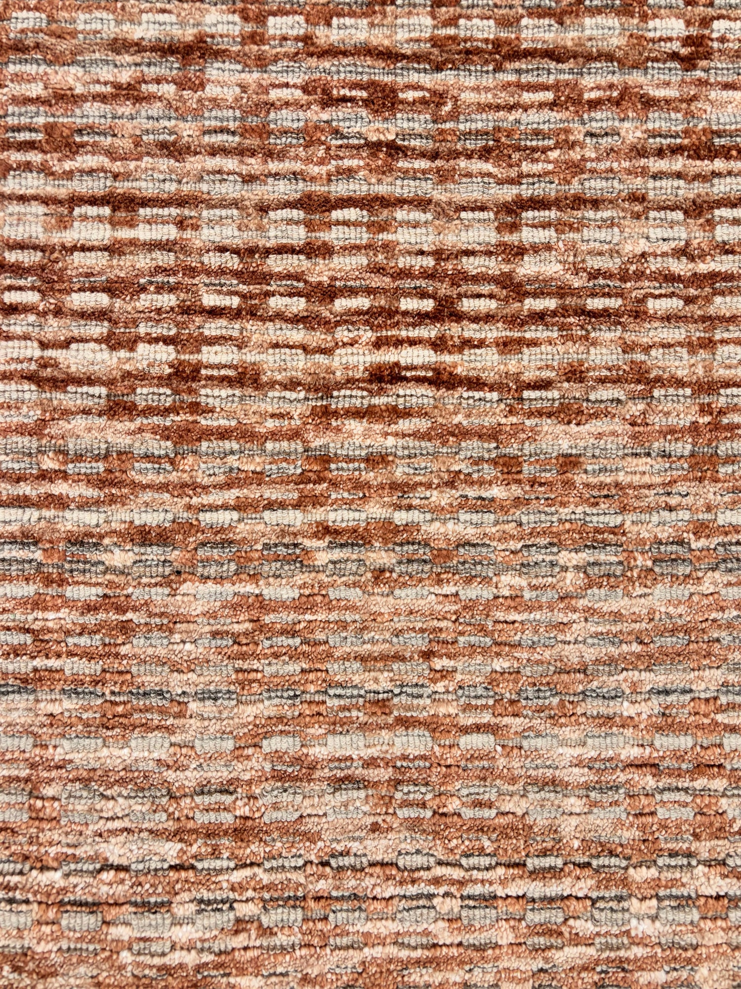 Handknotted rug sample with a strié textural design in orange, grey and ivory.