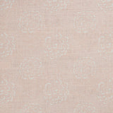 Detail of a printed linen fabric in a repeating camellia pattern in white on a light pink field.