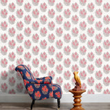 Armchair and end table in front of a wall papered in a floral cameo print in dusty rose, gray and white.