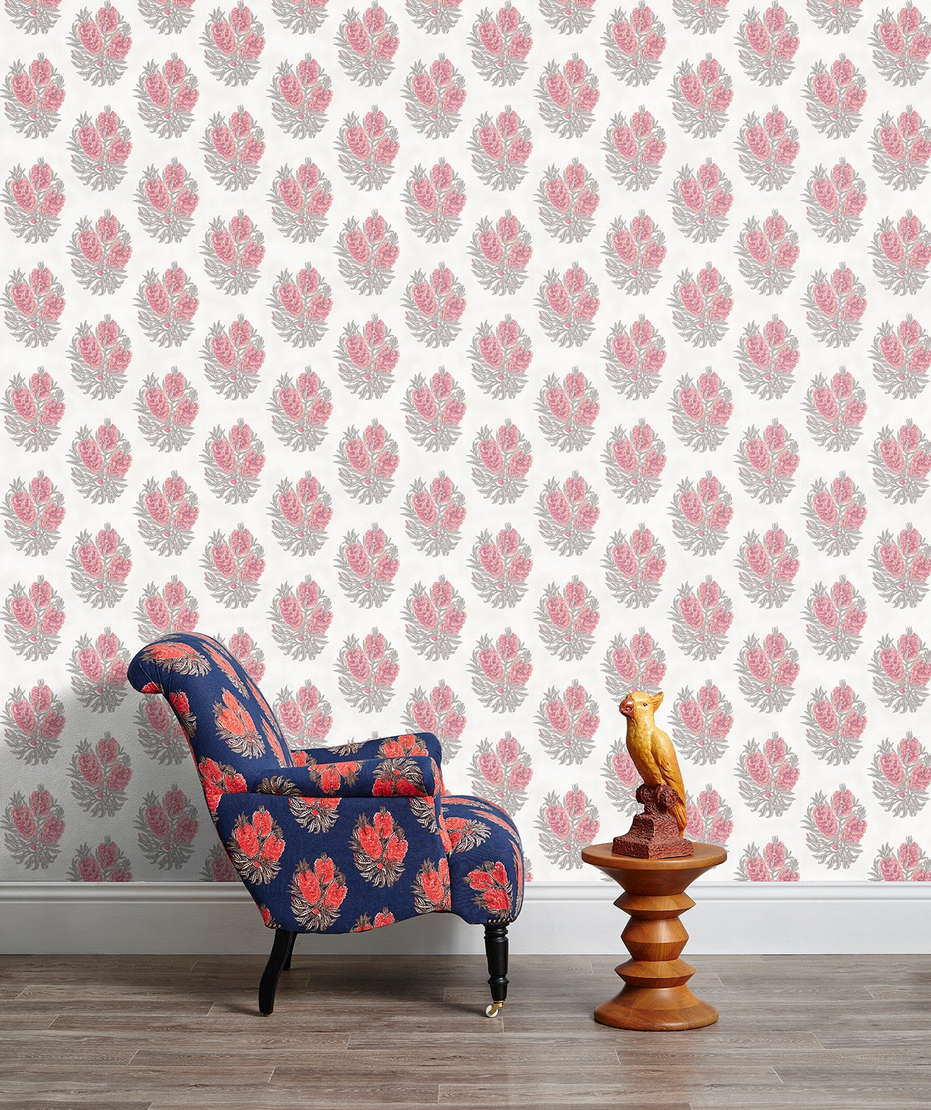 Armchair and end table in front of a wall papered in a floral cameo print in dusty rose, gray and white.