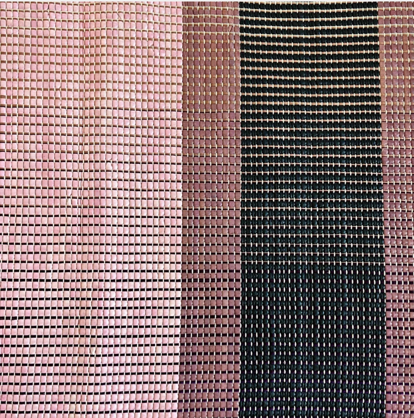 Close-up of a woven leather rug in an irregular stripe print in shades of pink, purple and black.