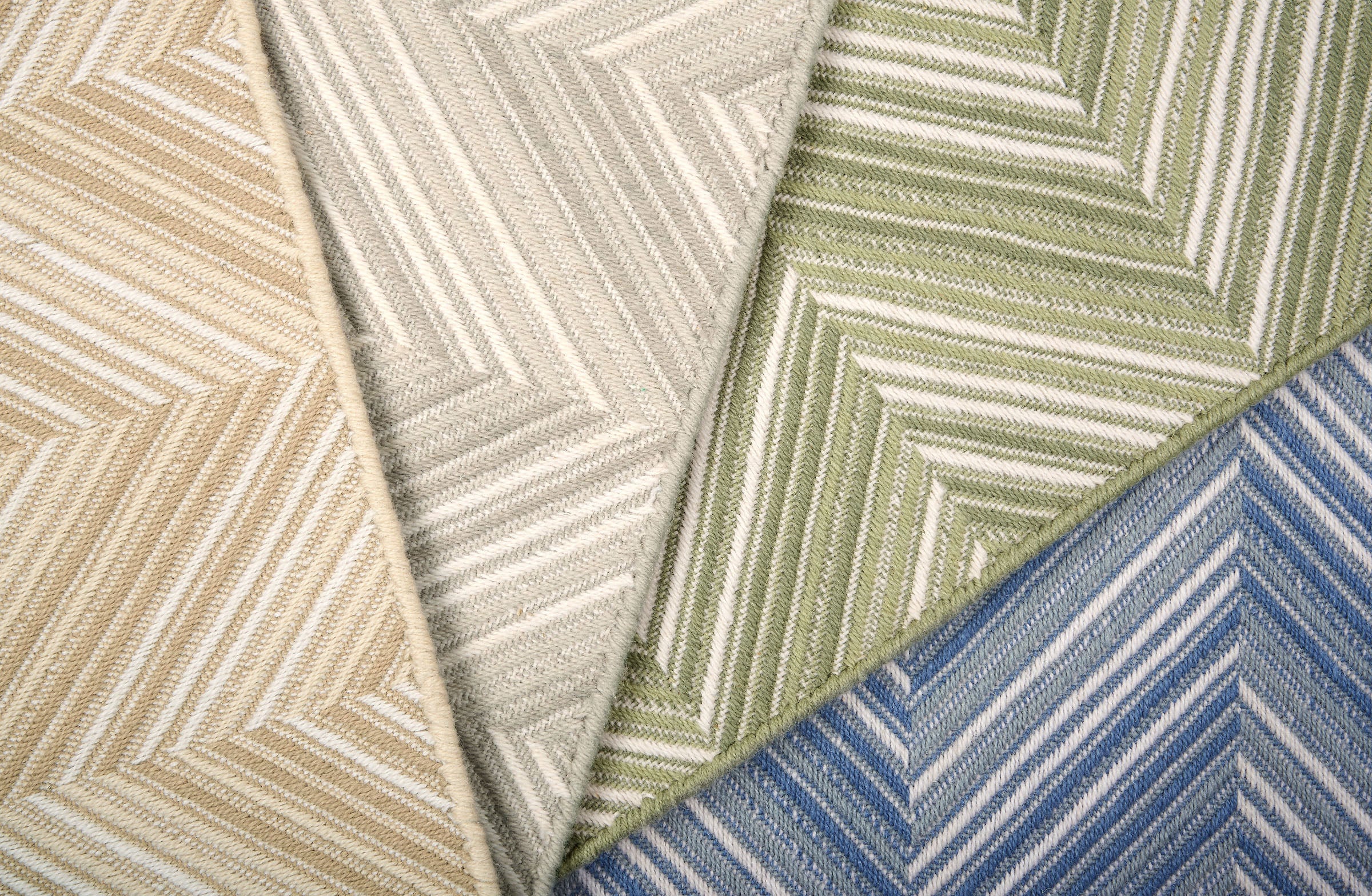 Broadloom carpet in zig zag pattern in tan, grey, green and blue. 