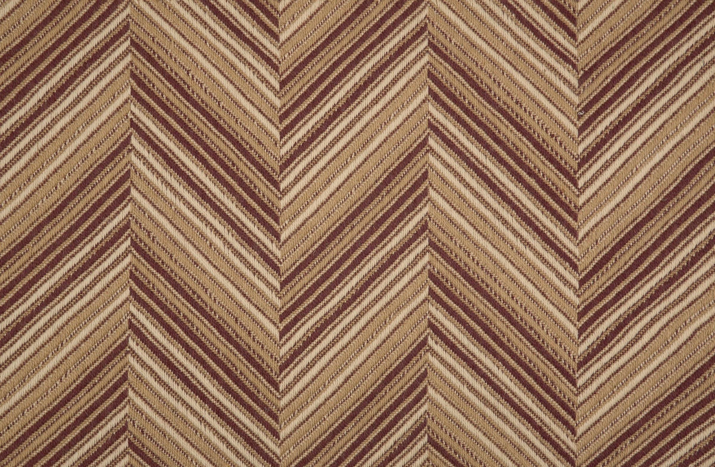 Broadloom carpet with a graphic herringbone pattern in shades of brown. 