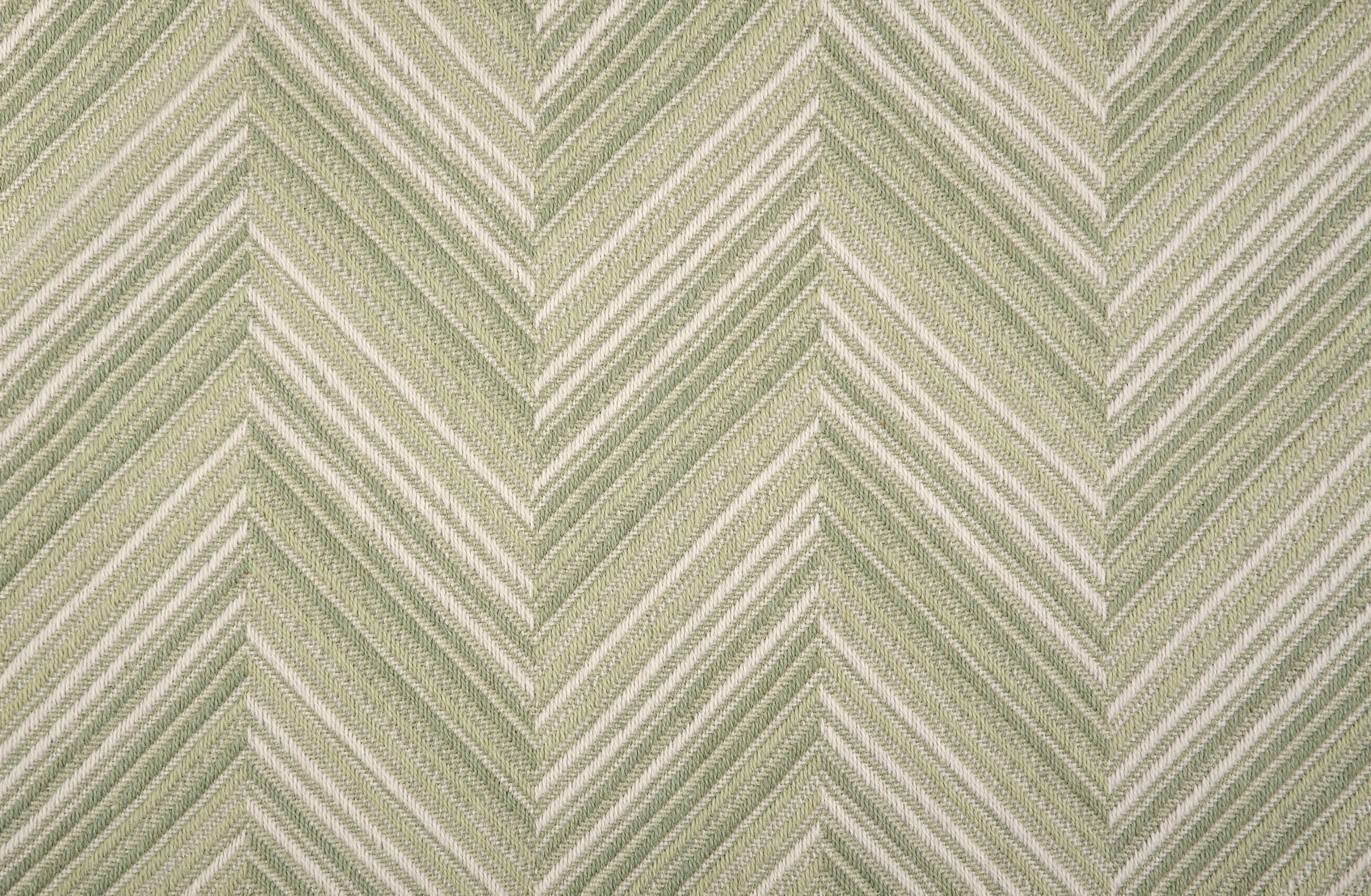 Broadloom carpet with a graphic herringbone pattern in shades of pastel green and white. 