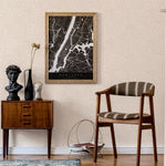 A midcentury inspired living room with a wall papered in a painterly abstract print in white on a cream field.