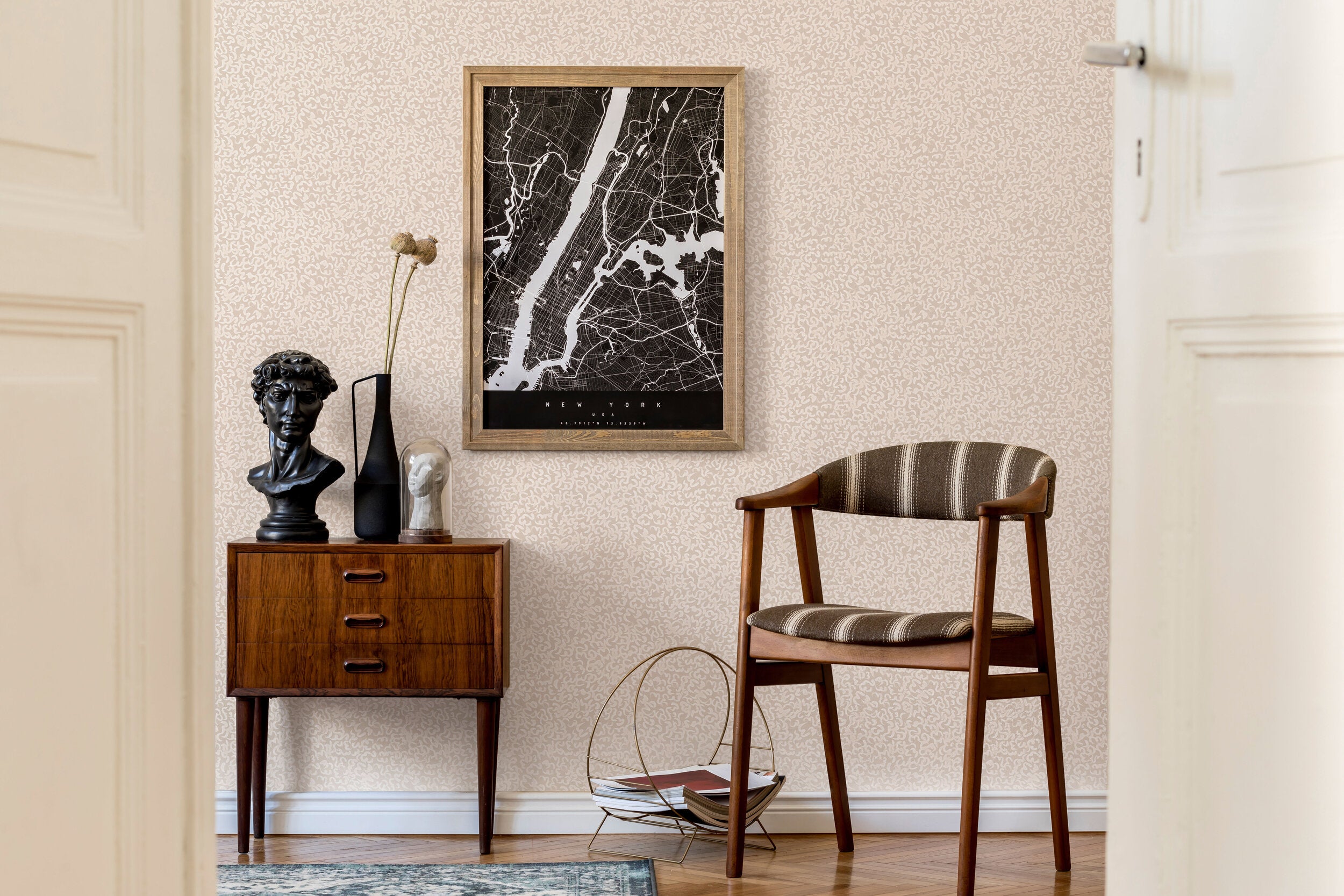 A midcentury inspired living room with a wall papered in a painterly abstract print in white on a cream field.