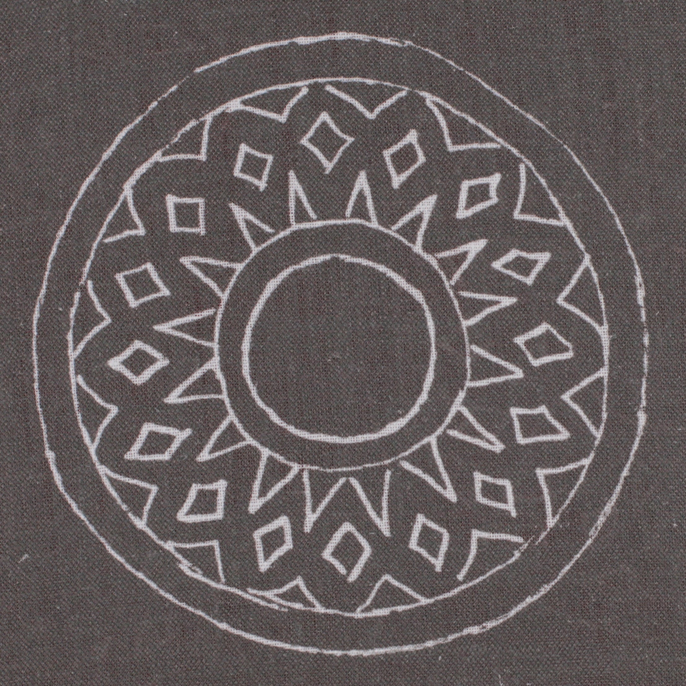 Detail of fabric in a repeating circular geometric print in light gray on a charcoal field.