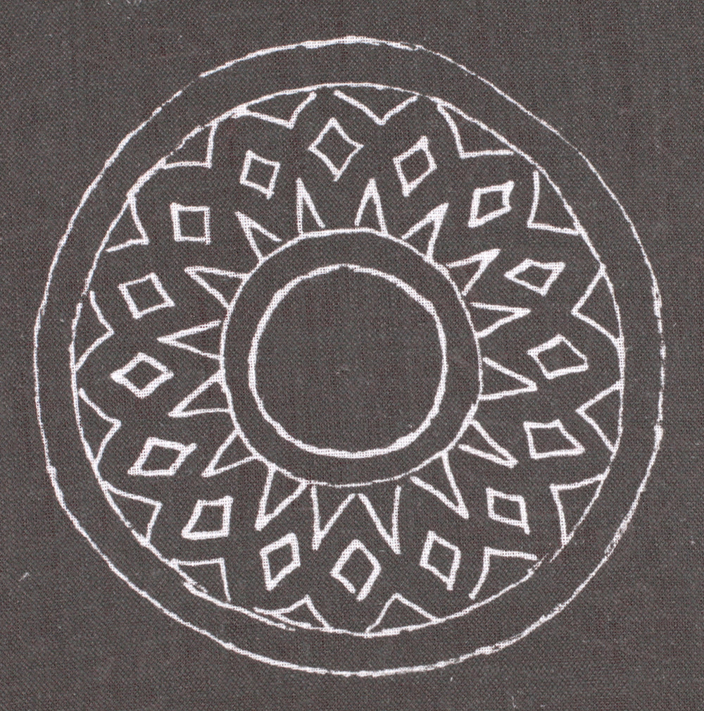 Detail of fabric in a repeating circular geometric print in white on a charcoal field.