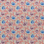 Printed linen fabric in a repeating china rose pattern in shades of pink, blue and cream on a coral field.