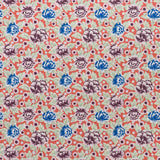 Printed linen fabric in a repeating china rose pattern in shades of pink, blue and cream on a coral field.