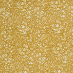 Detail of a printed linen fabric in a repeating chrysanthemum pattern in white on a mustard field.