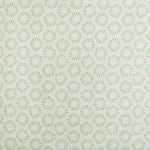 Detail of fabric in a playful circular print in green on a greige field.