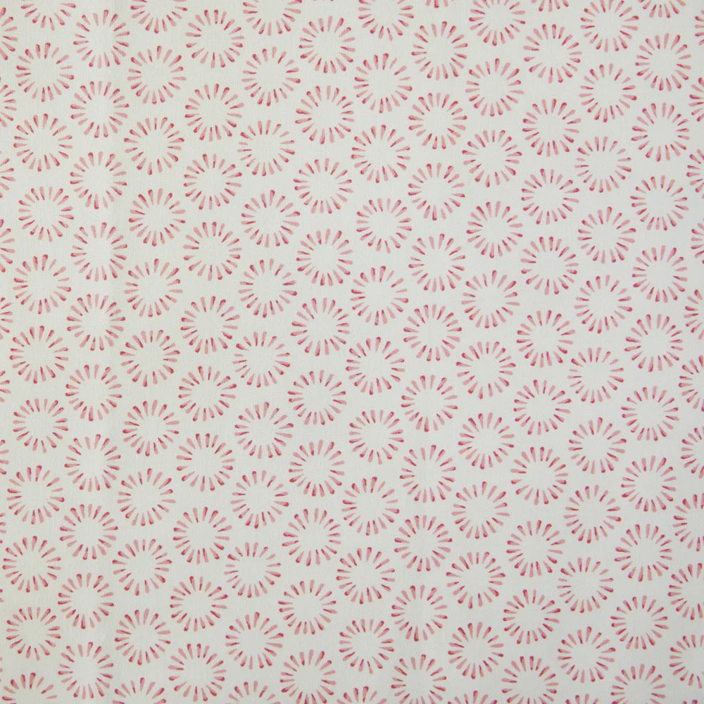 Detail of fabric in a playful circular print in pink on a greige field.