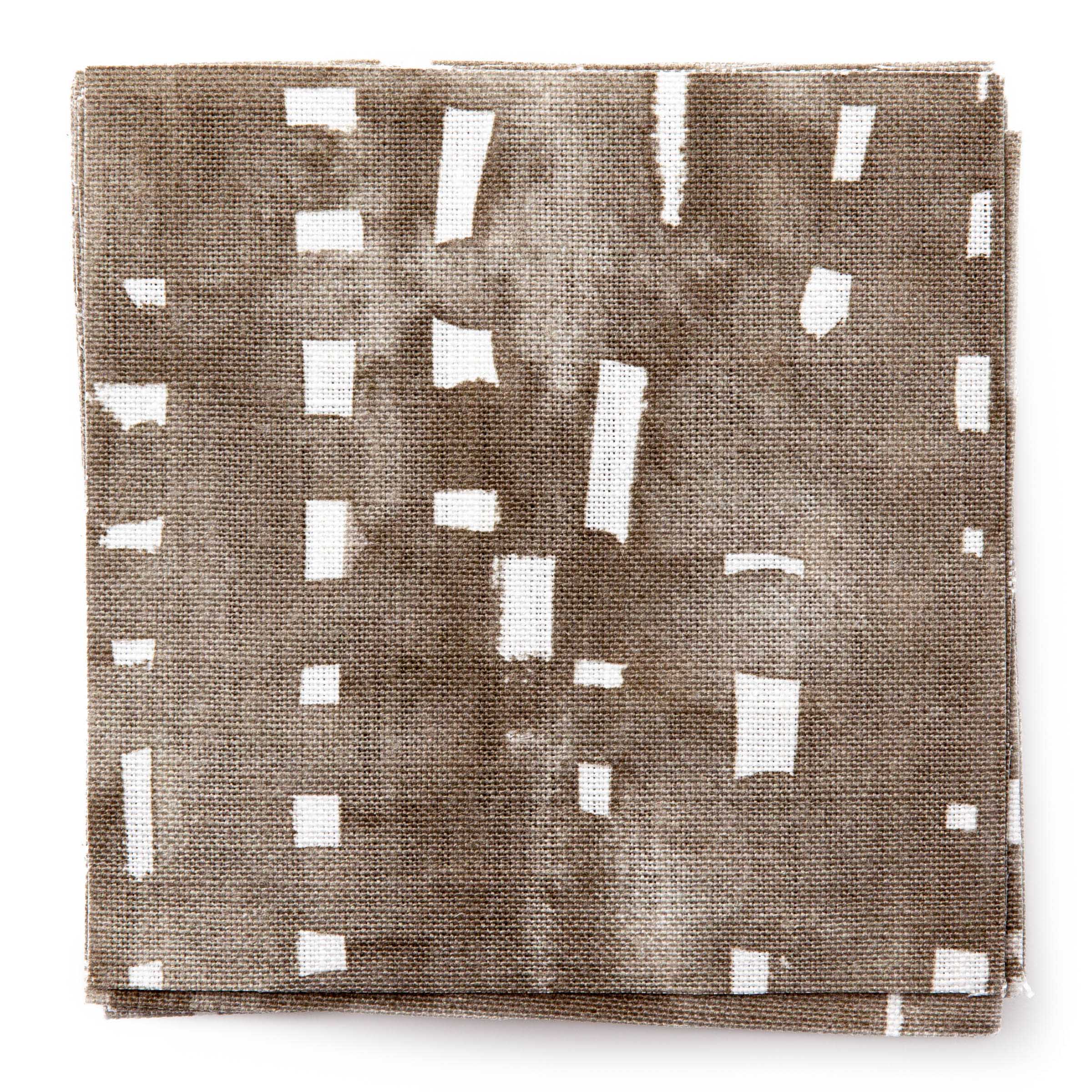 A stack of fabric swatches in a painterly small-scale grid print in brown on a white field.