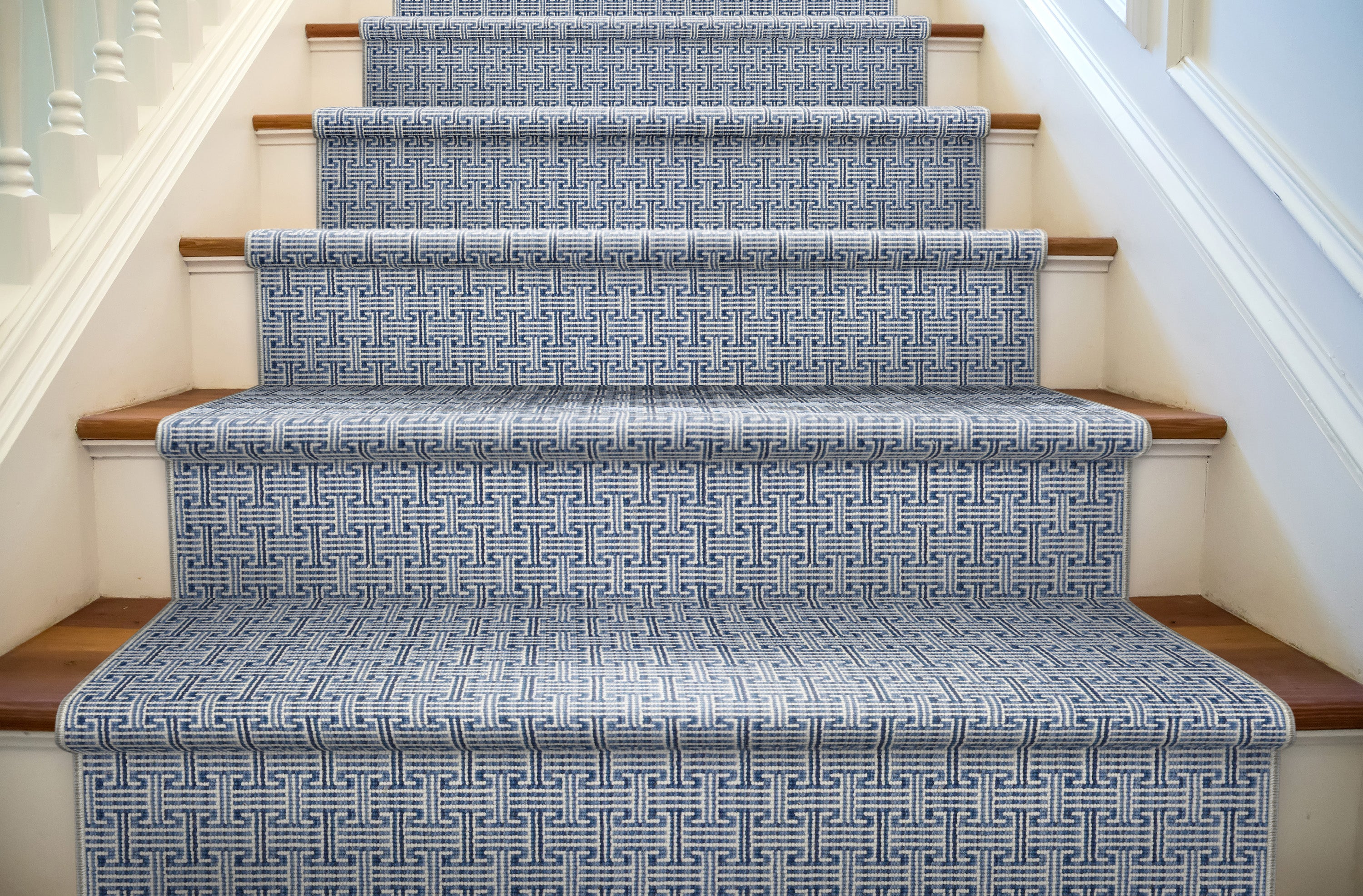 Staircase with patterned blue and white runner on wooden steps.