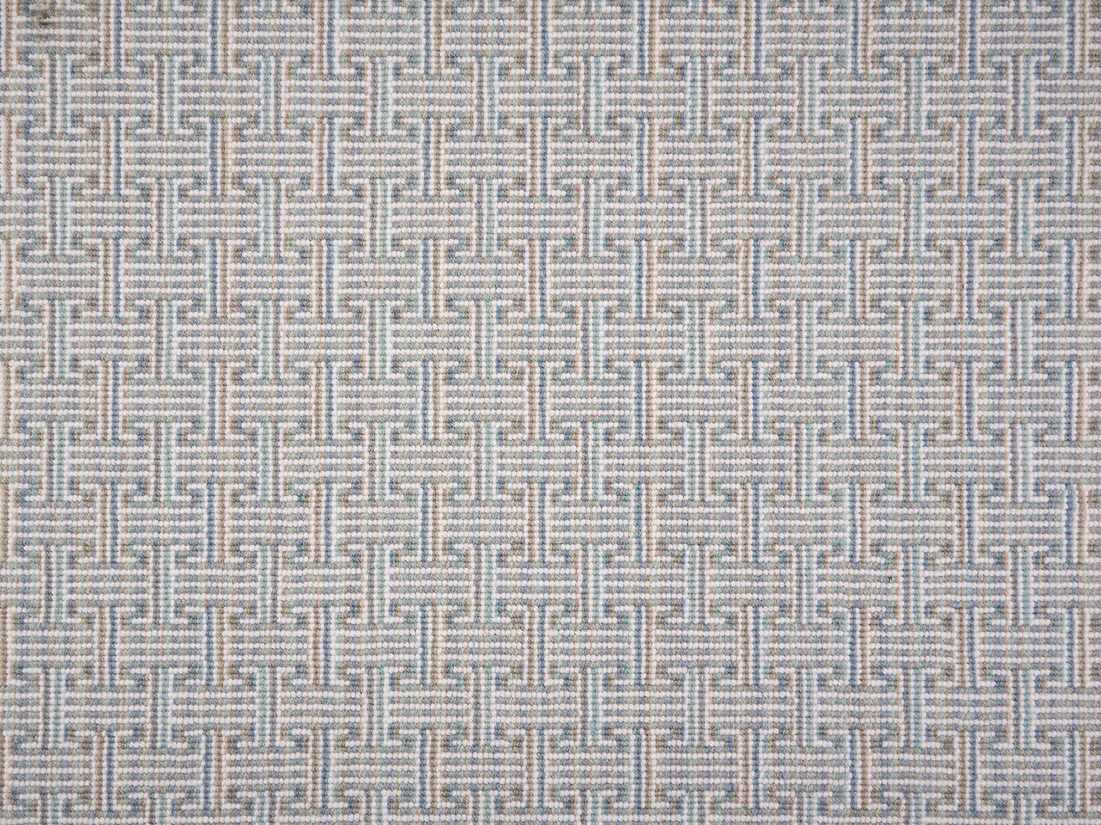 Patterned carpet with a geometric design in blue, grey tan, green and white