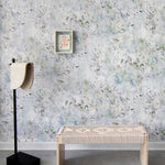 A modernist living tableau with a wall papered in an abstract painted print in blue, green, yellow and white.