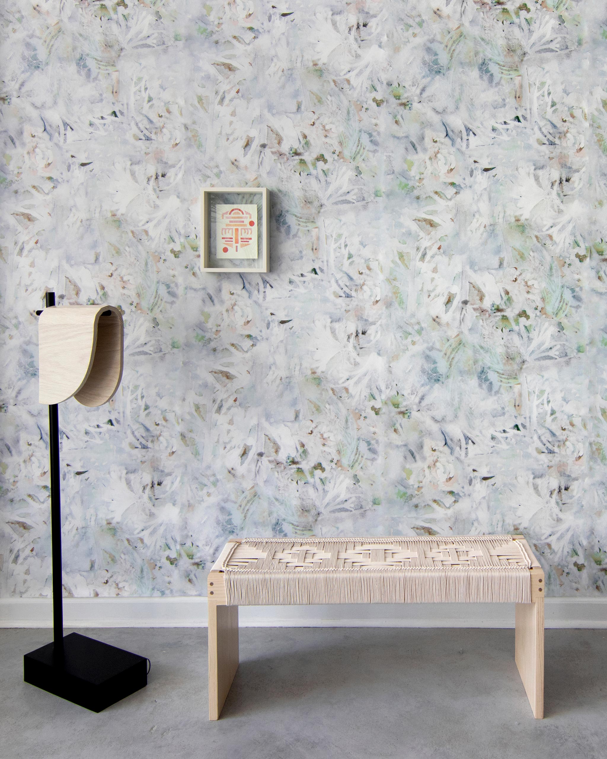A modernist living tableau with a wall papered in an abstract painted print in blue, green, yellow and white.