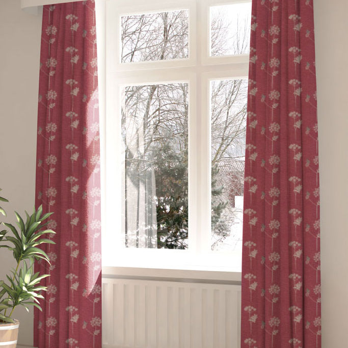 A large, sunny window with long curtains in a flower and butterfly print on a red field.