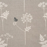 Detail of fabric in a playful flower and butterfly print in white and charcoal on a light gray field.