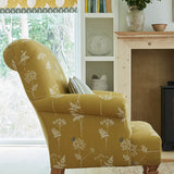 A cozy living space with an armchair upholstered in a mustard yellow flower and butterfly print.