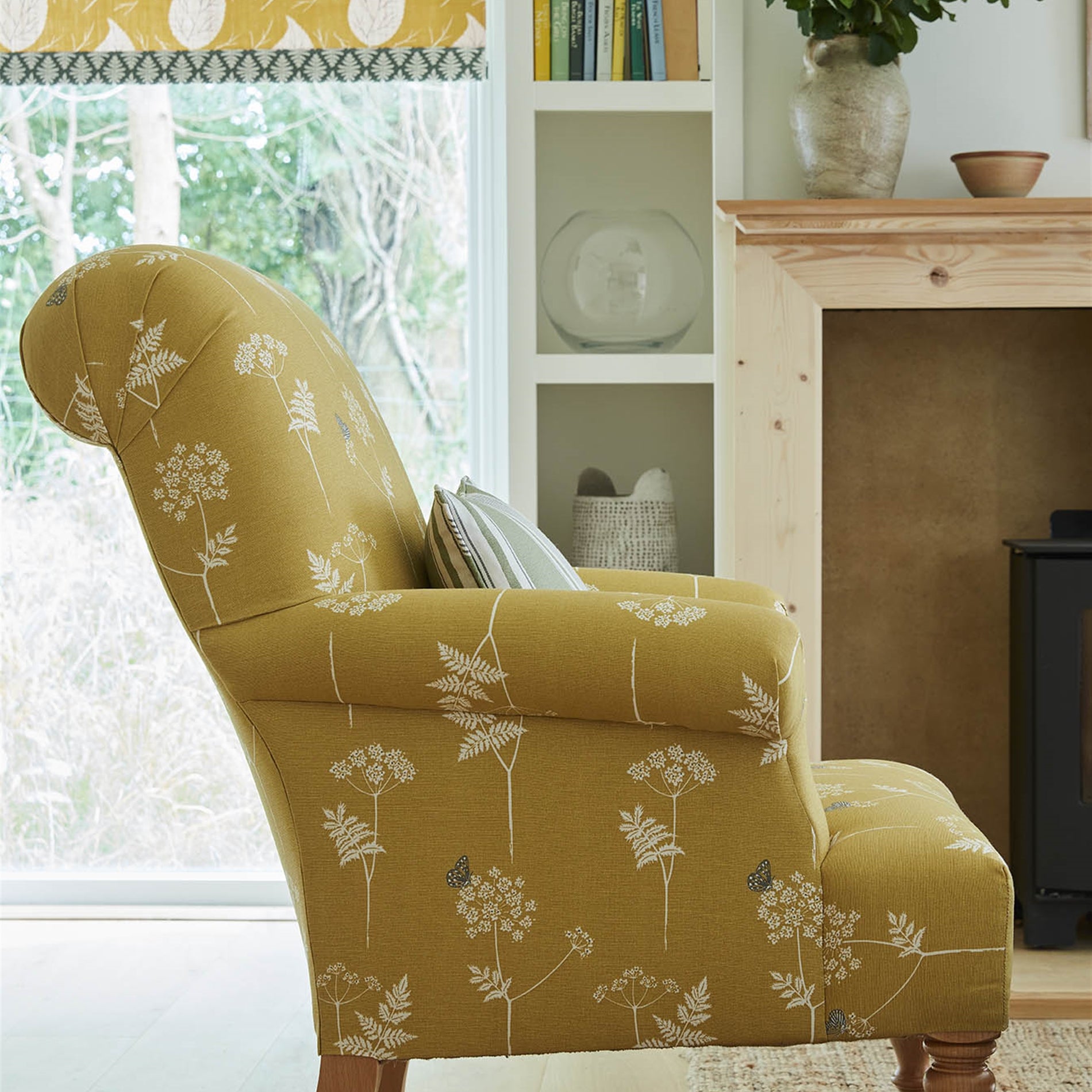 A cozy living space with an armchair upholstered in a mustard yellow flower and butterfly print.