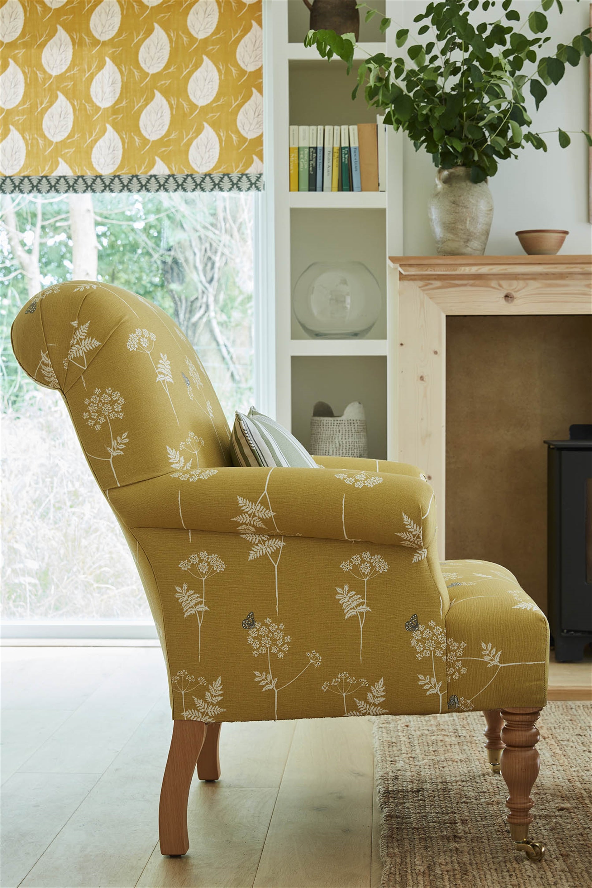 A cozy living space with an armchair upholstered in a mustard yellow flower and butterfly print.