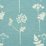 Detail of fabric in a playful flower and butterfly print in cream and tan on a blue field.