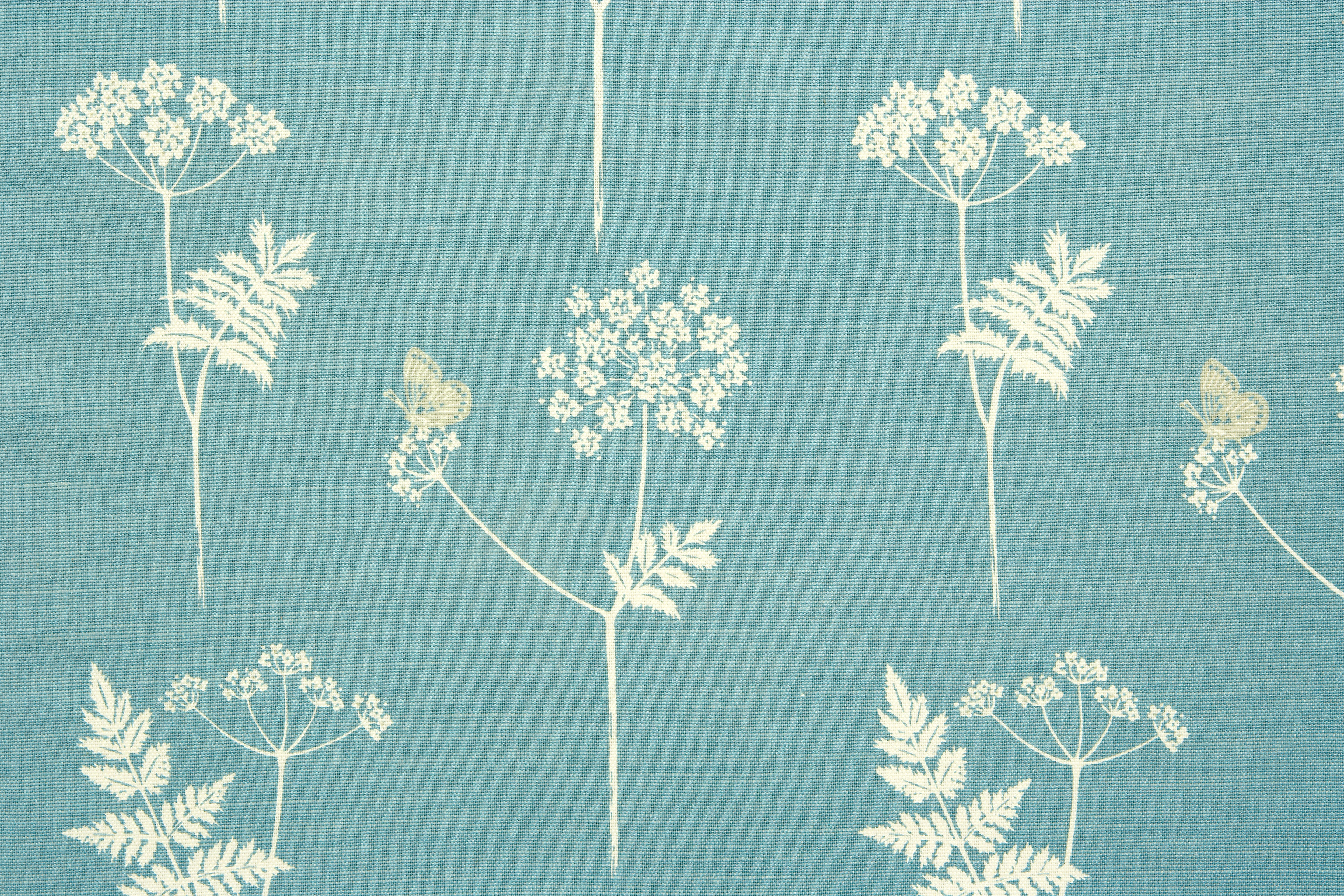 Detail of fabric in a playful flower and butterfly print in cream and tan on a blue field.