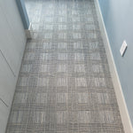 Patterned check blue carpet in a hallway with light blue walls.