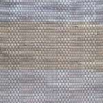 Close-up of a woven leather rug in a striped gray and tan colorway.