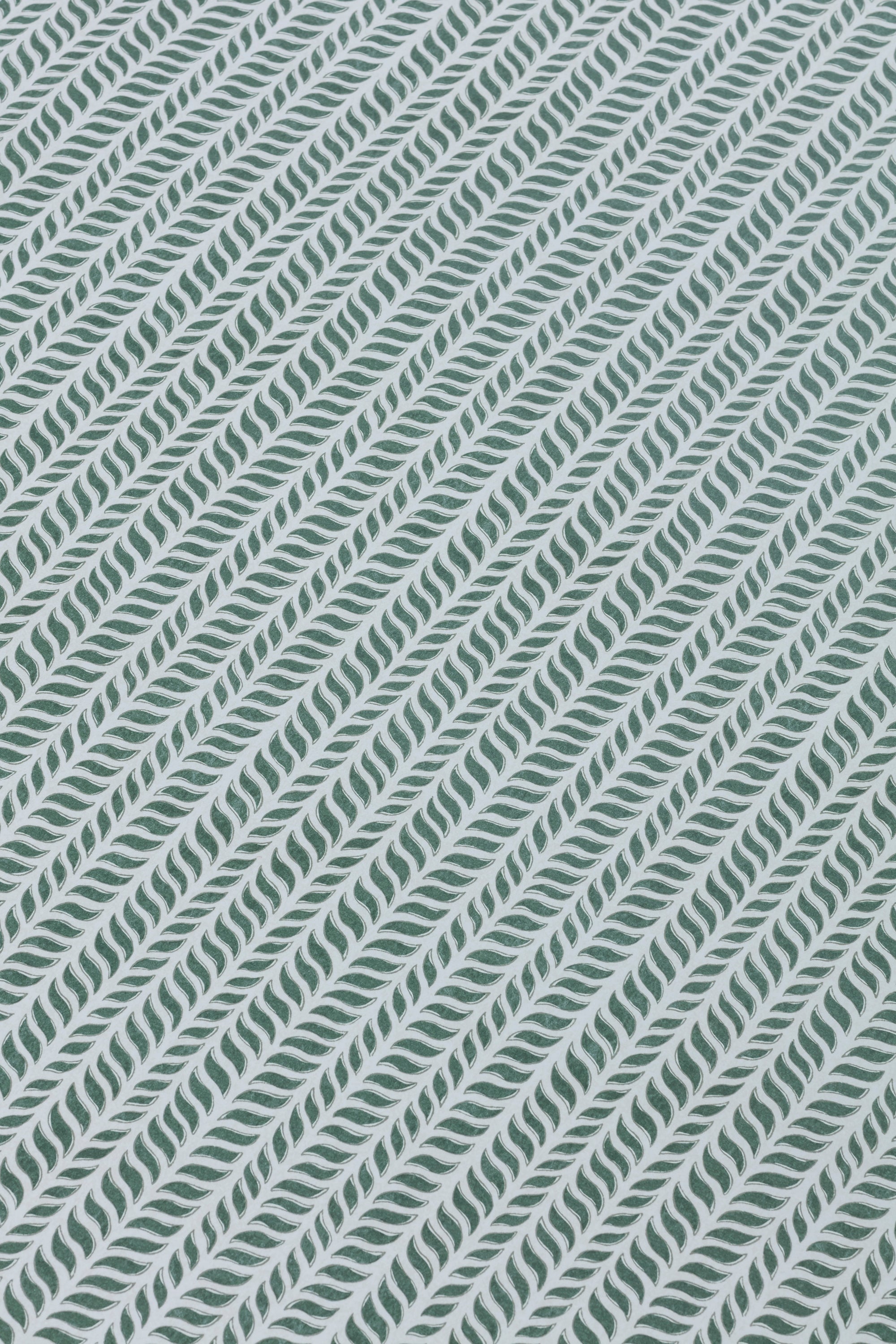 Detail of a wallpaper panel in a painterly herringbone print in olive on a light blue field.