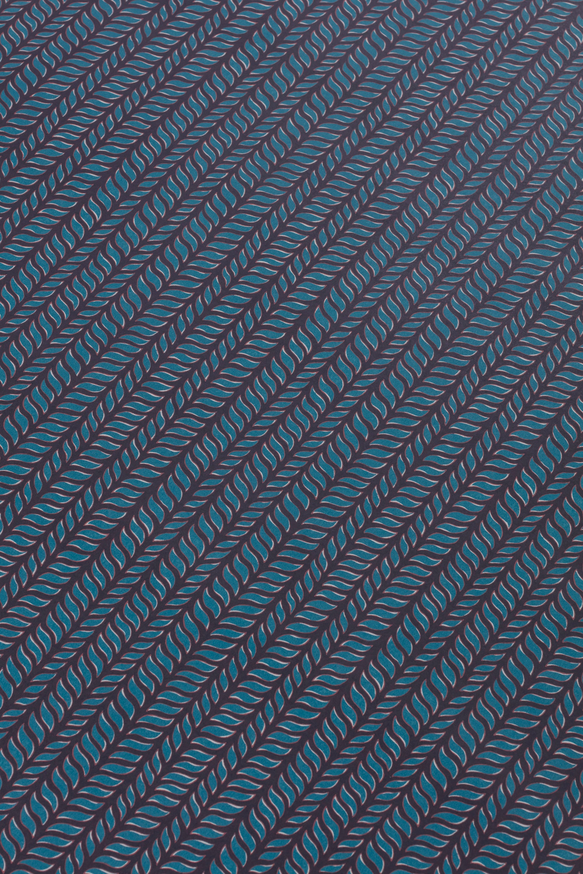 Detail of a wallpaper panel in a painterly herringbone print in turquoise and pink on a navy field.