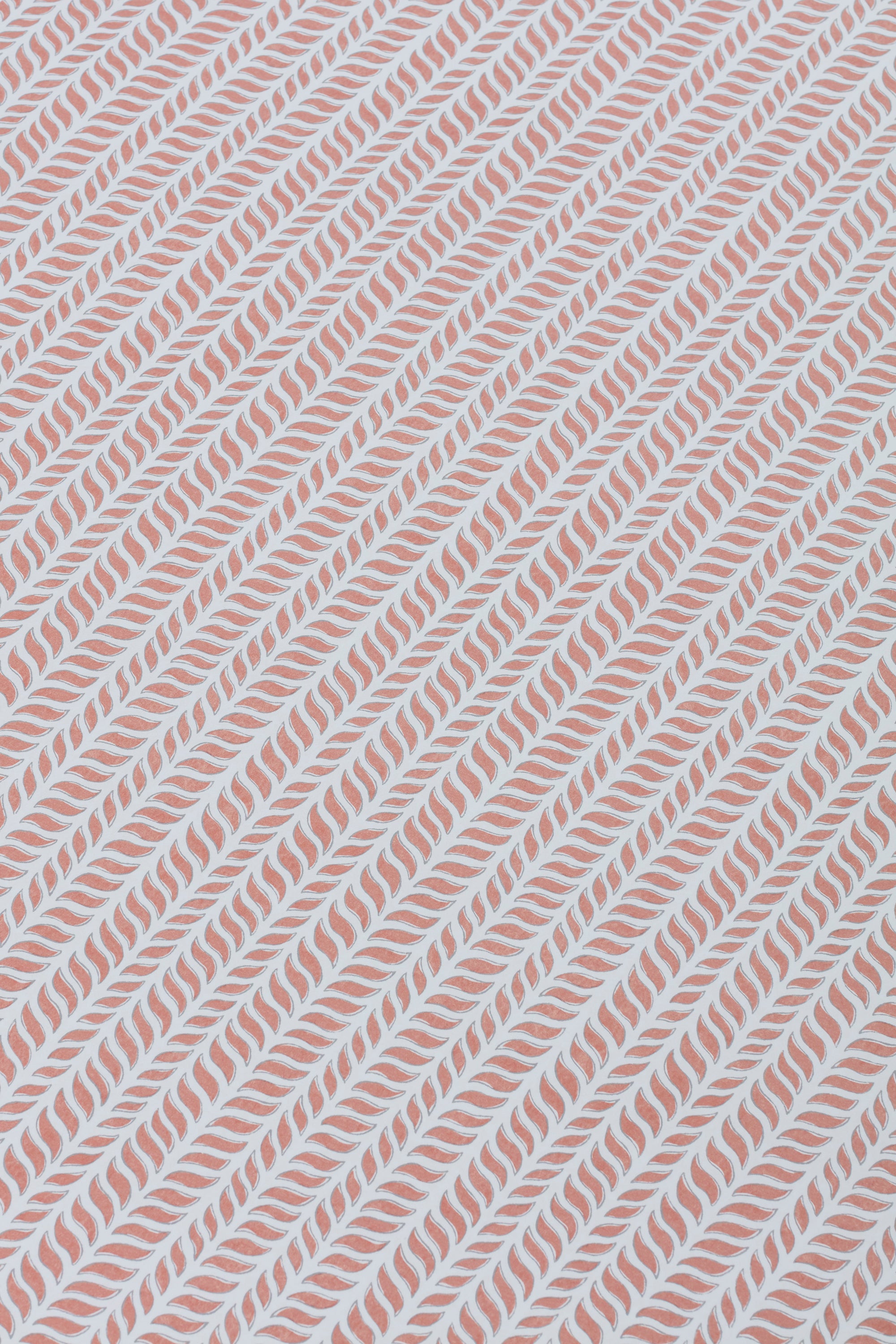 Detail of a wallpaper panel in a painterly herringbone print in pink on a light blue field.